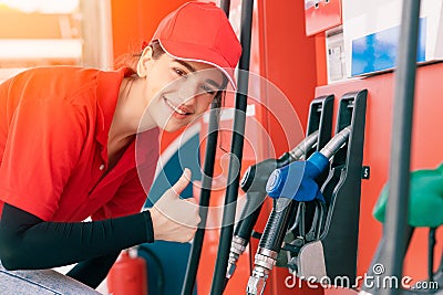 Gas station women worker staff Thumbs up at fuel nozzle dispensers happy service working refill cars gasoline Stock Photo