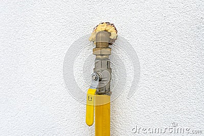 Gas valve located on the facade of the building, supplying gas to the boiler room, with a yellow handle. Stock Photo