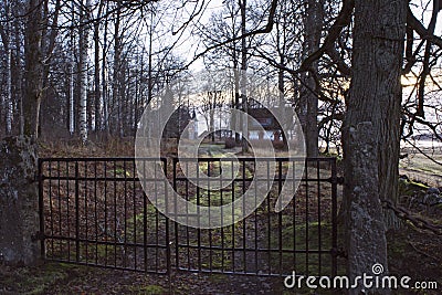 Gate in front of little white cottage in mysterious forest. Stock Photo