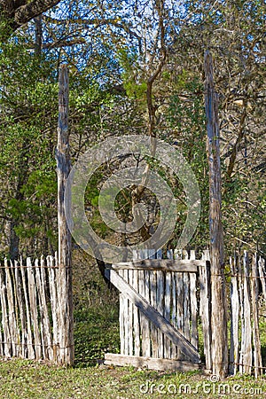A gate partially open leading into the woods Stock Photo
