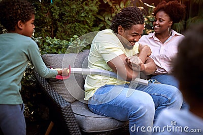 Gathered african family. Son playing and teasing father with plastic sword Stock Photo