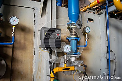 Gauges in the boiler room near the heating pipes with insulation coating. Stock Photo