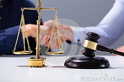 Gavel And Golden Justice Scale In Front Of Shaking Hands Stock Photo