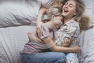 Gay lesbian couple of young girls are lying in bed laughing and cuddling, top view. Concept of love, gay marriage and pride Stock Photo