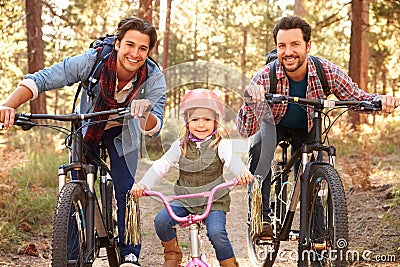 Gay Male Couple With Daughter Cycling Through Fall Woodland Stock Photo