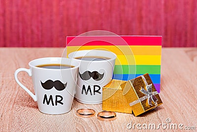 Two cups of coffee, gay flag and a gift box with marriage ring Stock Photo