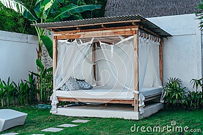 Gazebo with a wooden bed under a mosquito grid on a outside Stock Photo