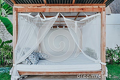 Gazebo with a wooden bed under a mosquito grid on a outside Stock Photo