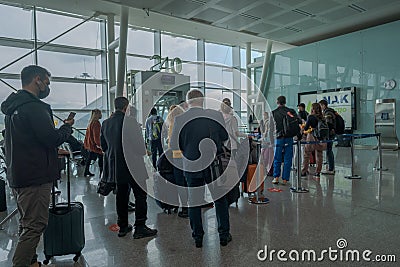 People with mask wait in a line in front of flight gate and air personnel check their temperature in Aydin Menderes Airport Editorial Stock Photo