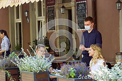 Gdansk, North Poland - August 15, 2020: A male waiter in a restaurant serving customer and making living while wearing protective Editorial Stock Photo