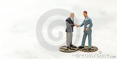 Gear concept in business. Businessmen in suits shake hands and stand on gears. Hiring a new employee, contracting Stock Photo
