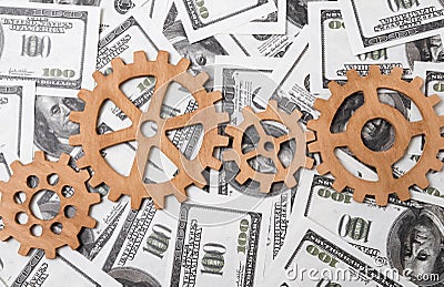 Gears made of wood on the background of dollar bills. Stock Photo