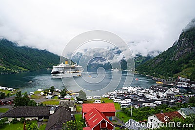 Geiranger, Norway - January 25, 2010: ship in norwegian fjord on cloudy sky. Ocean liner in village harbor. Travel destination, to Editorial Stock Photo