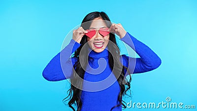 Gelukkige jonge vrouw die twee kleine papieren harten vasthoudt aan haar ogen geïsoleerd op blauwe achtergrond stock video Gelukkige jonge vrouw die twee kleine papieren harten vasthoudt aan haar ogen geïsoleerd op blauwe achtergrond stock video
