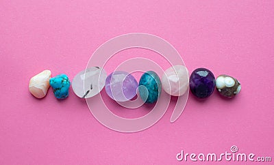 Gemstone minerals on a pink background. Round tumbling minerals of amethyst, rose quartz, apatite, turquoise, agate Stock Photo