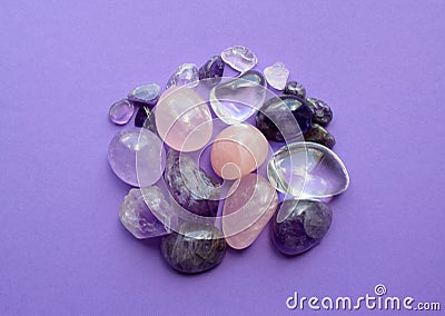Gemstone minerals on a purple background. Round tumbling minerals of amethyst and amethyst crystal Stock Photo