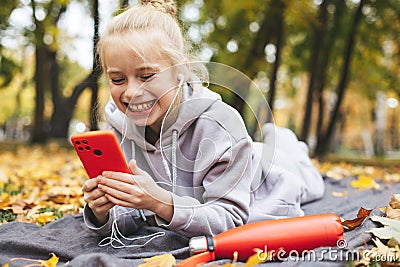 Gen z teenage girl using smartphote outdoors in autumn time. Stock Photo