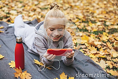 Gen z teenage girl using smartphote outdoors in autumn time. Stock Photo