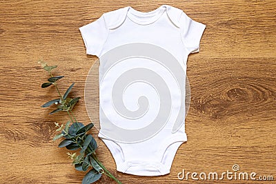 Gender neutral blank white babygrow on a wam wooden background Stock Photo