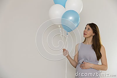 Gender reveal party. Pregnant woman holding blue and white balloons Stock Photo