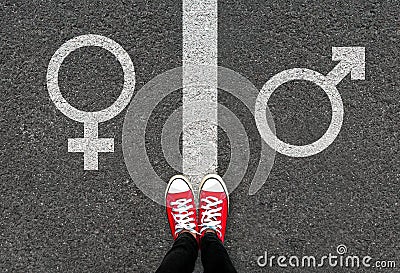 Gender symbols of love on asphalt background. Selfie feet and red sneaker shoes with male and female white sign on road. Stock Photo