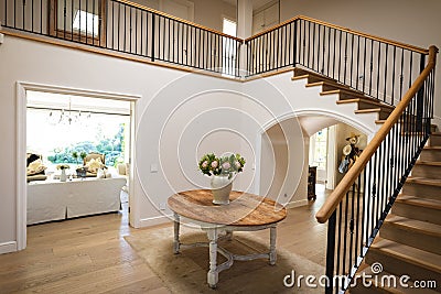 General view of house interior with table and vase with flowers in spacious hallway and staircase Stock Photo