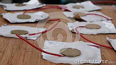 Generation of electricity from foil, brass coin, salt solution and cotton wool. Chemical experiments in the kitchen. Homemade salt Stock Photo