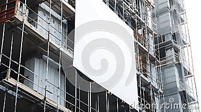 Generative AI Blank white banner for advertisement hanging on the scaffolding of modern building under constructio Stock Photo