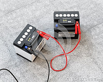 Generic maintenance-free car batteries connected by jumper cable on concrete ground Stock Photo