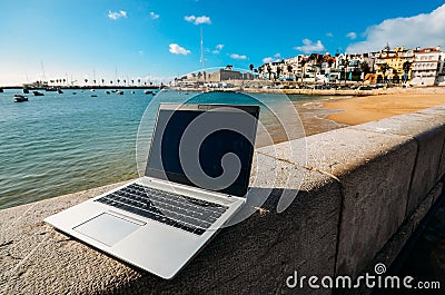 Generic notebook laptop on sunny deserted sandy beach background Editorial Stock Photo