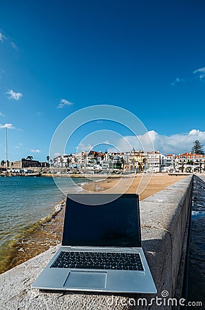 Generic notebook laptop on sunny deserted sandy beach background Editorial Stock Photo