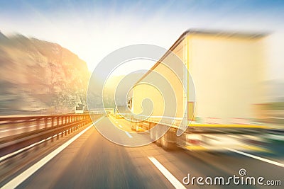 Generic semi trucks speeding on the highway at sunset Stock Photo