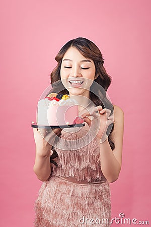 Generous woman holding birthday cake front pink background Stock Photo