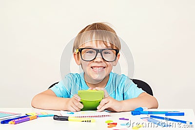 Genius boy in glasses is sitting at desk. Happy boy doing homework at home. Cute clever boy in glasses studying. Back to school. C Stock Photo