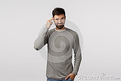 Genius, mindful shopping, good choice. Attractive and sassy, confident macho man with beard in grey sweater, tap temple Stock Photo