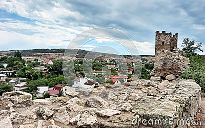 Genoese fortress in the Crimea on the background of houses. A ruined ancient tower made of stones and blocks in the city. Stock Photo