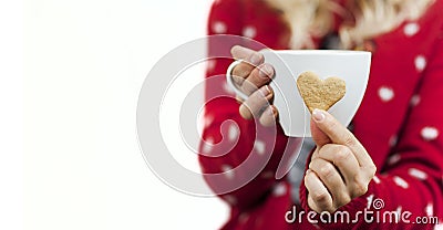 Gentle beautiful girl hands hold bright tasty sweet Christmas heart-shaped cookies with a mug of tea Stock Photo