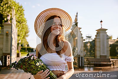 Gentle beautiful young woman holding wildflower bouquet in park Stock Photo