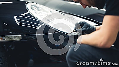 Gentle black car paint touch-ups done with a small brush in the area of headlights. Focused car detailing expert during Stock Photo