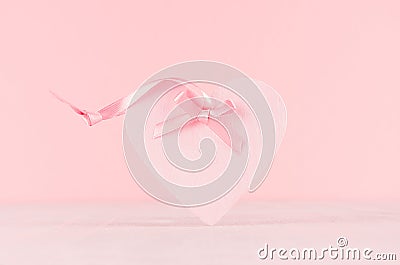 Gentle decor for Valentine days - soft light pink heart with ribbon on white wood board, closeup. Stock Photo