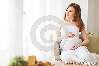 Gentle elegant pregnant woman in a white dress Stock Photo