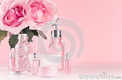 Gentle girlish dressing table with flowers, cosmetics products - rose oil, bath salt, cream, perfume, cotton towel, bottle, bowl. Stock Photo