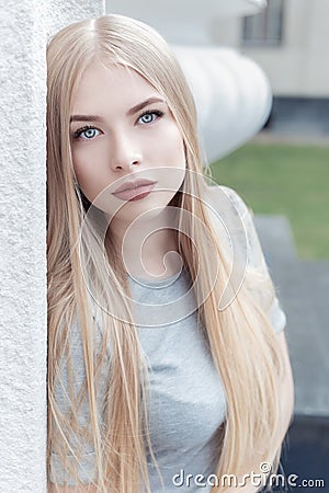 Gentle portrait of a beautiful cute girl with long blond hair with full lips and blue eyes in a gray suit, look at the camera Stock Photo