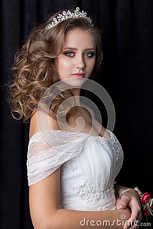 Gentle portrait of a beautiful cute happy bride with a beautiful hairdo festive bright make-up in a wedding dress with earrings an Stock Photo