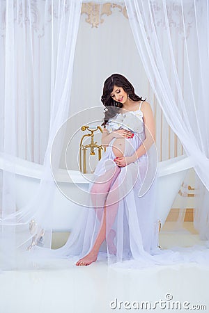 Gentle pregnancy. Beautiful pregnant in light white dress with orchids Stock Photo