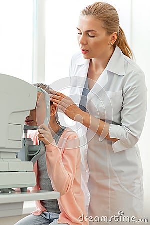 Gentle serious ophthalmologist correcting position of her young patient Stock Photo