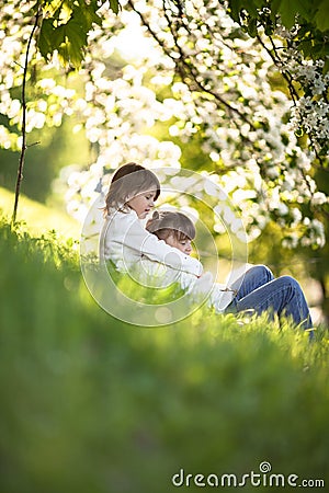 Gentle sisters hug apple blossom, sunny childhood Stock Photo