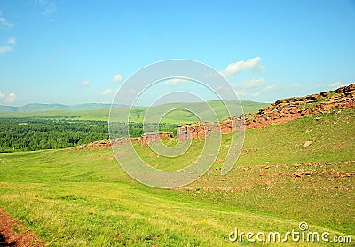 A gentle slope of a high hill with sheer stone cliffs at the top and a fertile pasture at the foot Stock Photo