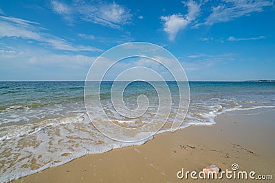 Gentle waves on an empty sandy beach with a calm ocean Stock Photo