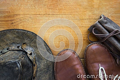 Genuine leather men`s hipster travel and hiking accessories hat shoes thermoflask carry case on aged wood background. Vintage Stock Photo